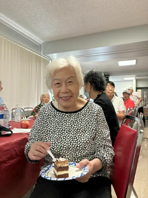A resident smiling while enjoying a slice of birthday cake