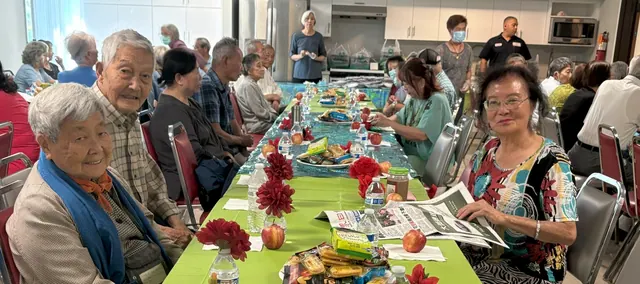 Residents seated at a long table with refreshments