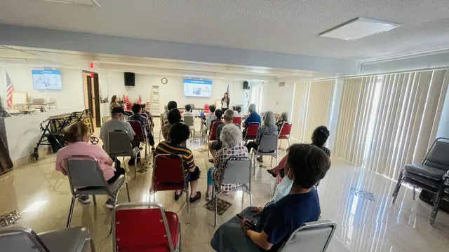 Wide view of the fraud prevention seminar, with residents facing the presentation screens