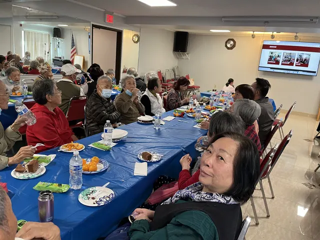 Residents dining and watching a screen presentation at the birthday party