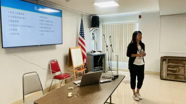 The presenter stands beside the projection screen introducing the fraud prevention seminar