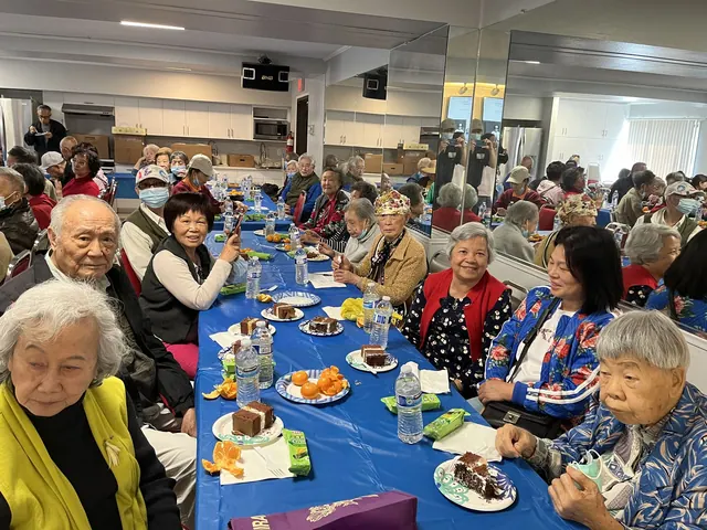 Residents smiling for a photo at the birthday party table