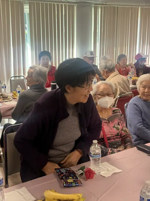 A staff member chatting with residents, with a gift and a rose on the table