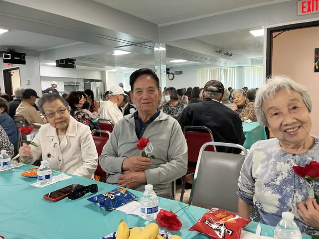 Residents holding red roses at the birthday party