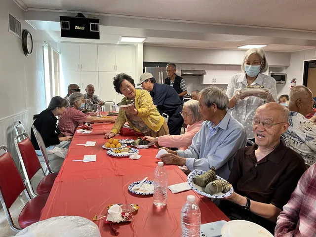 Residents seated at a long table enjoying zongzi and snacks