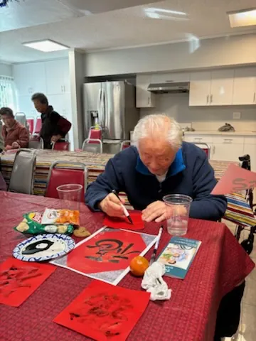 A resident writing New Year calligraphy at the table