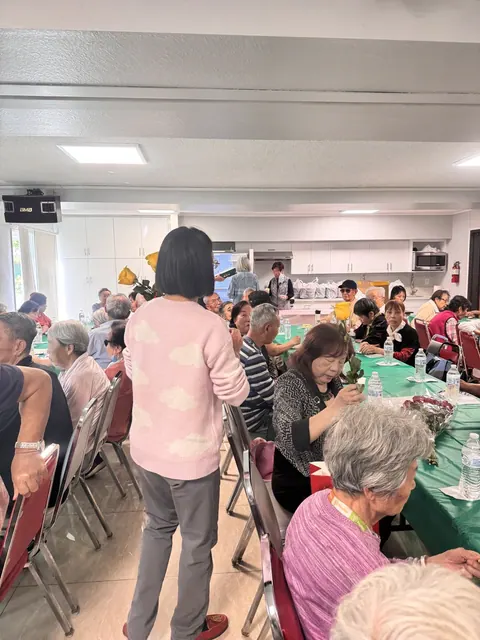 A staff member moving among the tables chatting with residents holding flowers