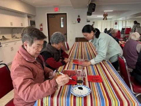 Residents writing "Fu" characters at a long table