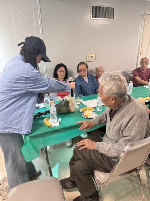A staff member passing the microphone to a resident to share a story about the most important woman in his life