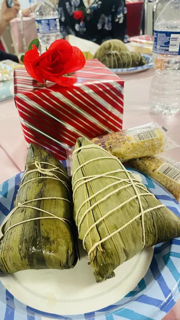 Rice dumplings (zongzi) on a plate beside a festive gift box