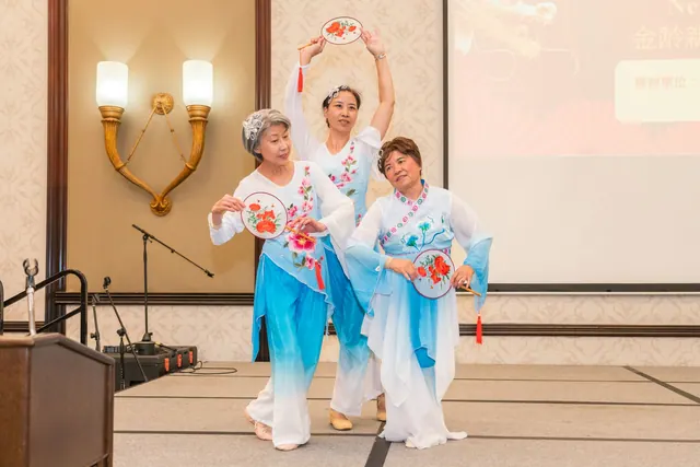 Dancers in blue and white costumes performing with round fans
