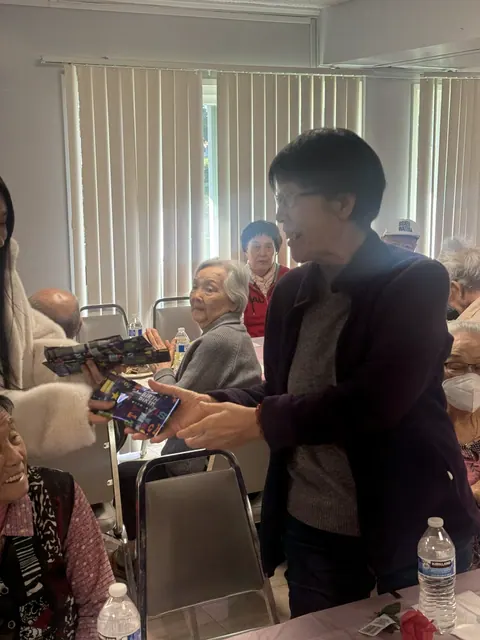 A staff member handing out birthday gifts to residents in the hall
