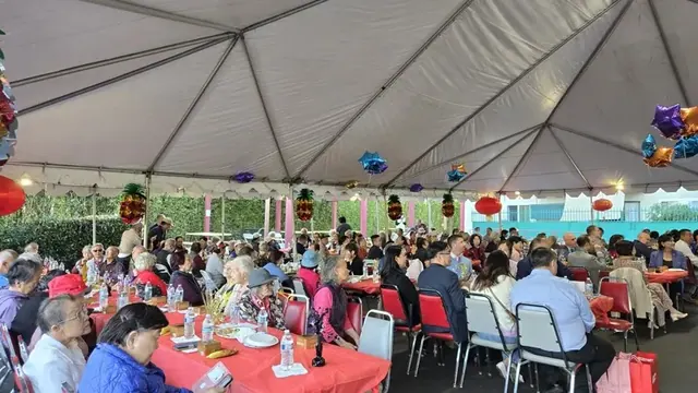 Residents and guests gather at banquet tables under the tent