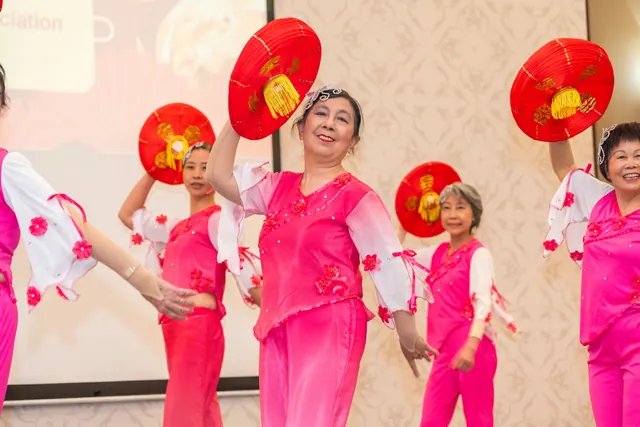 Senior dancers in pink costumes performing the lantern dance with red lanterns