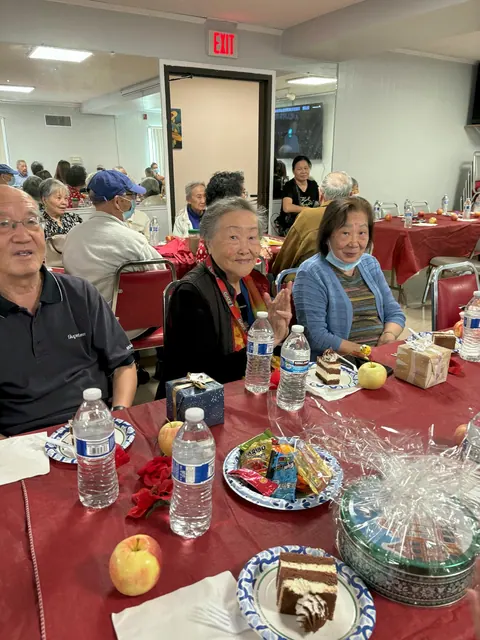 Residents gathered around a table with cake, fruit, and gifts