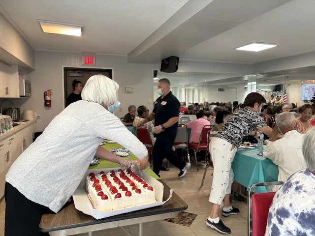 A volunteer cutting the strawberry birthday cake