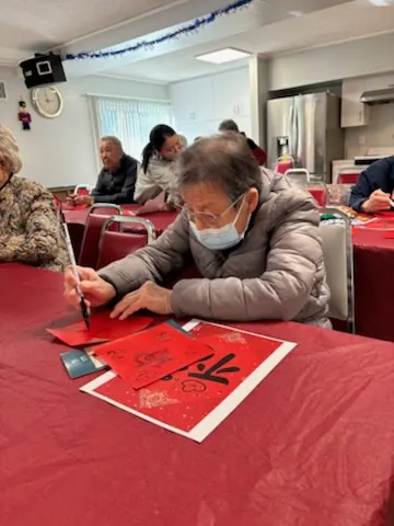 A resident writing a "Fu" character on red paper with a brush