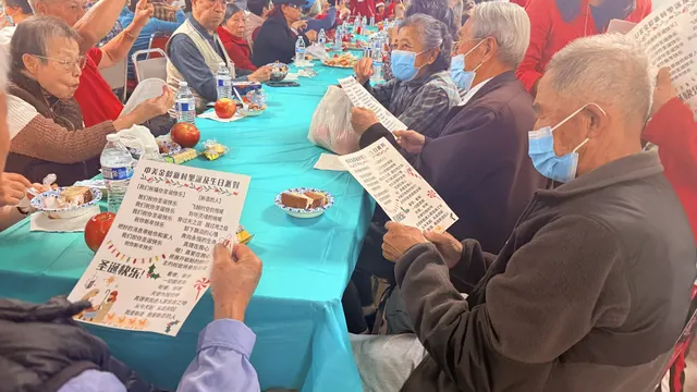 Residents seated around tables, following the lyrics and singing together