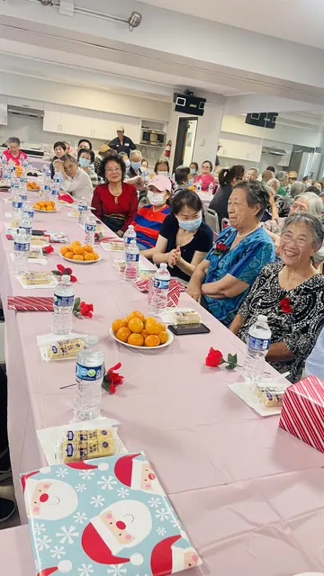 Residents seated along a long table with tangerines and snacks