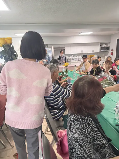 A resident holding a rose while listening to the sharing, with a staff member nearby