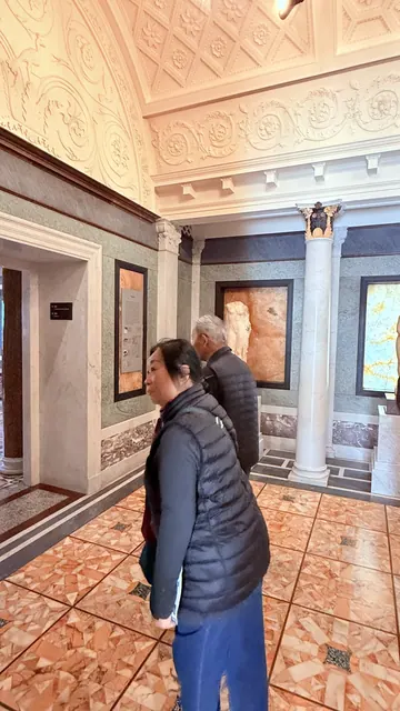 Residents touring an ornate gallery with marble floors and columns