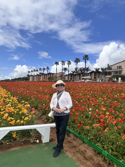A resident standing on a path among blooming red and orange flowers