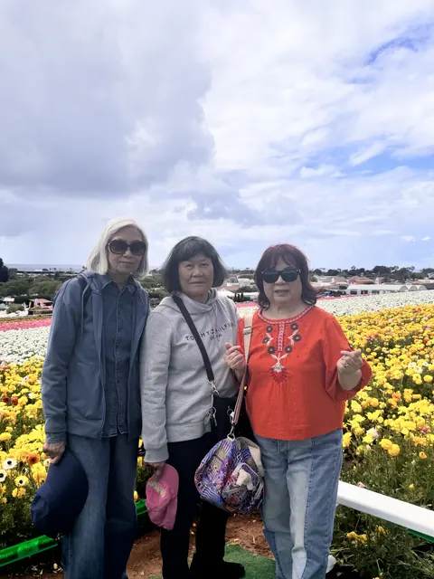 Three residents posing in front of fields of yellow and white blooms