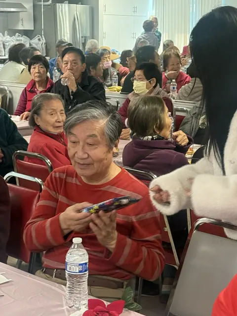 A resident smiling while holding a wrapped birthday gift at the table