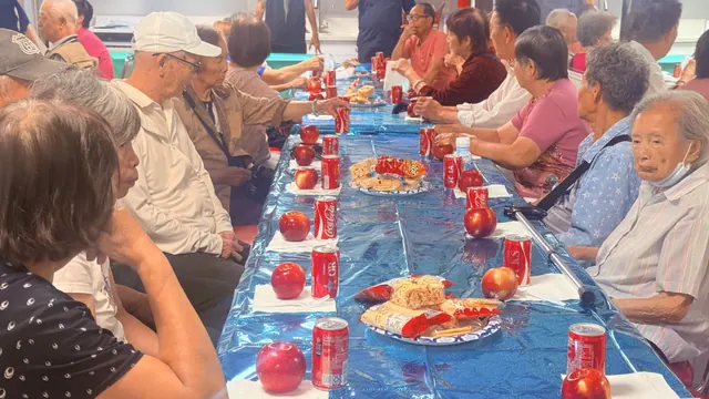 Residents seated along a long table at the birthday party