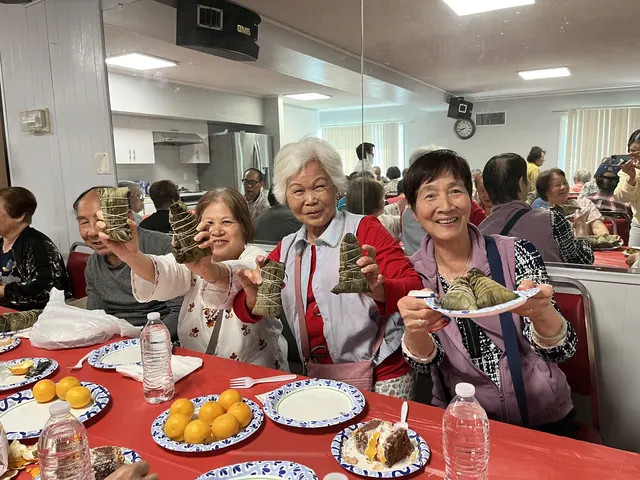 Residents holding up zongzi and smiling for the camera
