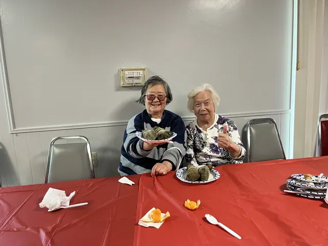 Two residents holding zongzi for a photo