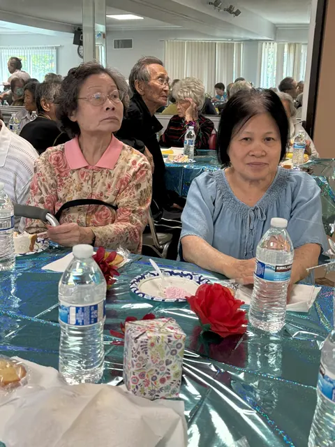 Residents seated at a decorated table with a small gift box and a red flower