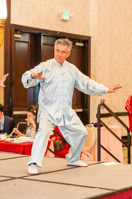 A senior performing tai chi on stage