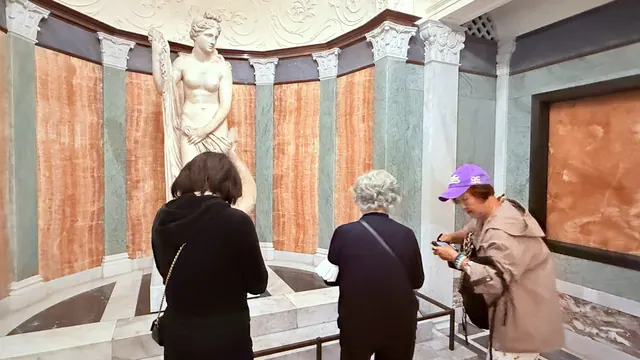 Residents admiring a classical marble statue displayed in a columned gallery