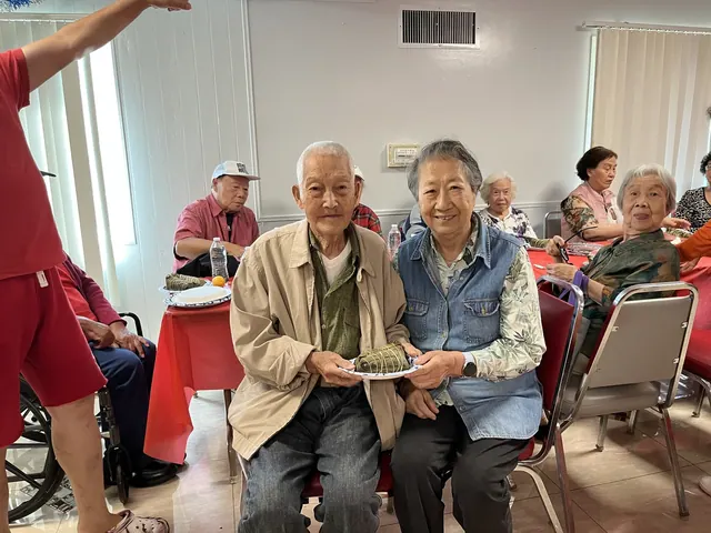 Two residents holding plates of zongzi