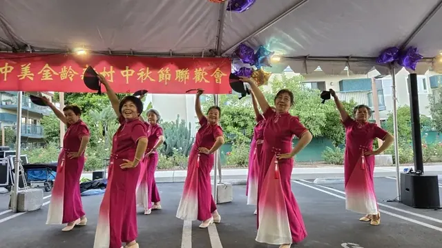 Residents perform a dance in pink qipao dresses